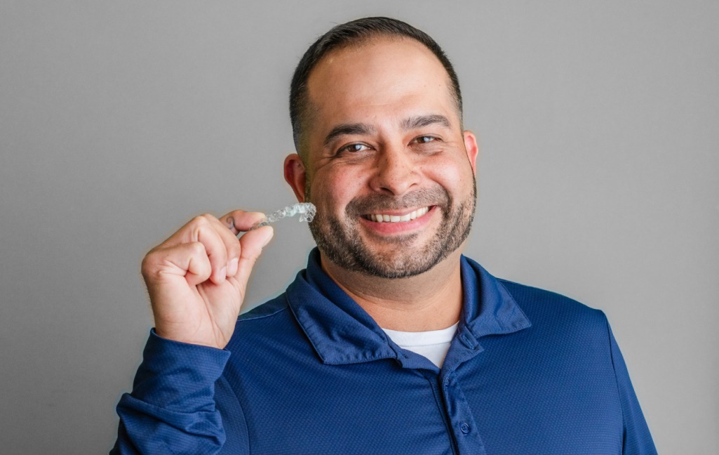 A man holding up an Invisalign aligner